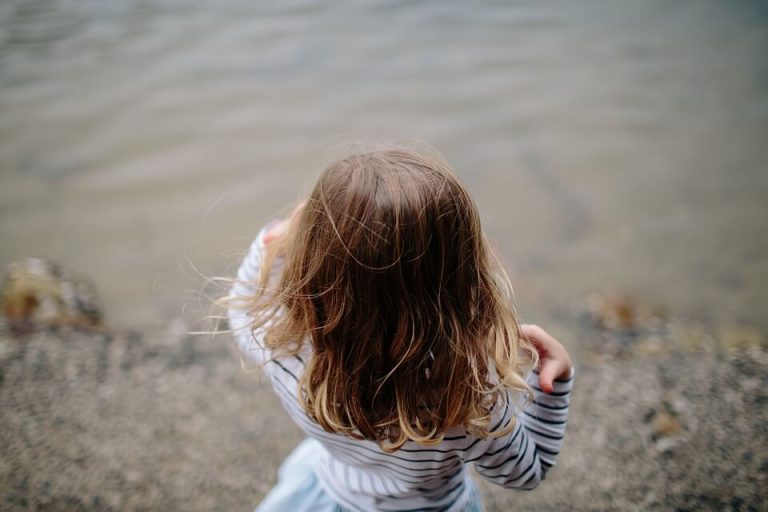 Dziewczynka o brązowych włosach stojąca nad wodą