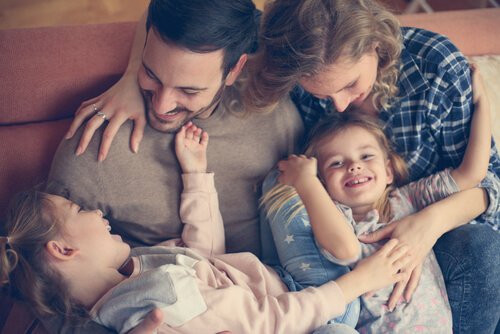 Przytulający się i roześmiani mama, tata i dwie córki - powody do radości w ciąży i wyrzeczenia