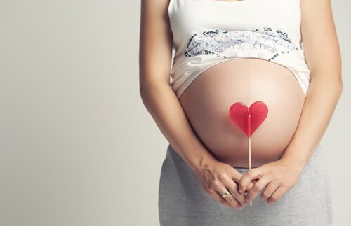 Brzuch kobiety w ciąży z lizakiem w kształcie serca