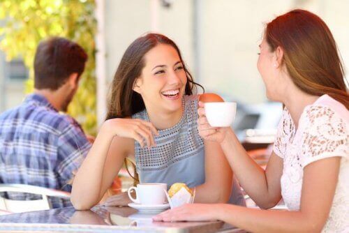 Dwie śmiejące się kobiety siedzące przy stoliku w kawiarni