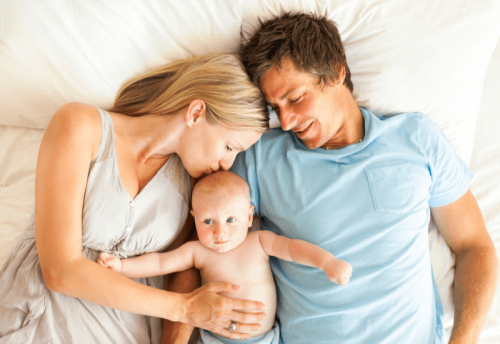 Mama i tata leżący w łóżku z niemowlęciem