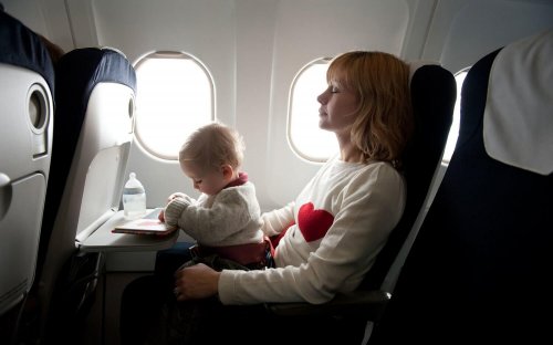 Mama z dzieckiem na kolanach lecących samolotem - podróżowanie z niemowlakiem