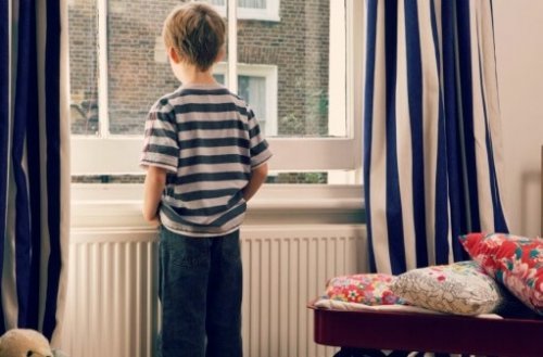 Smutny chłopiec stojący przed oknem