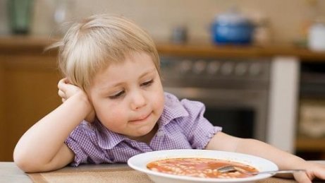 Dziecko opierające głowę na ręce, patrzące na zupę - dziecko nie chce jeść