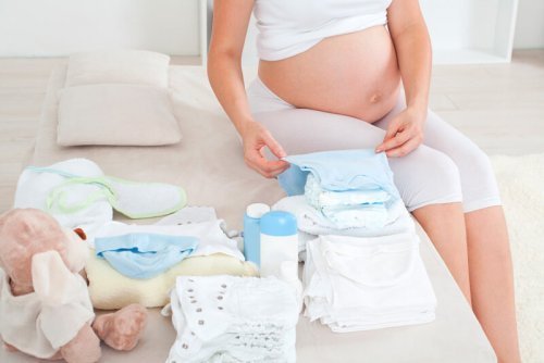 Kobieta w ciąży składająca ubranka dziecka