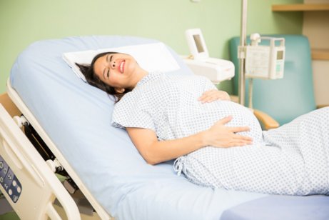 Kobieta w ciąży z bólami porodowymi na leżance