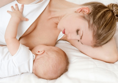 Mama leżąca z niemowlakiem ssącym pierś