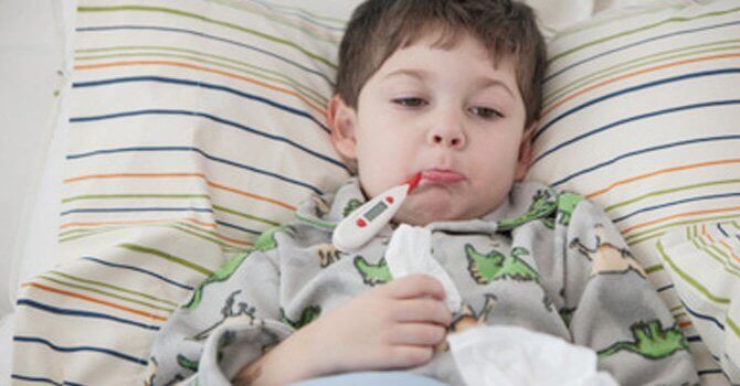 Chłopiec leżący w łóżku z termometrem w ustach - przeziębienie u dziecka