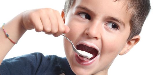 Chłopiec wkładający do ust łyżeczkę z jogurtem