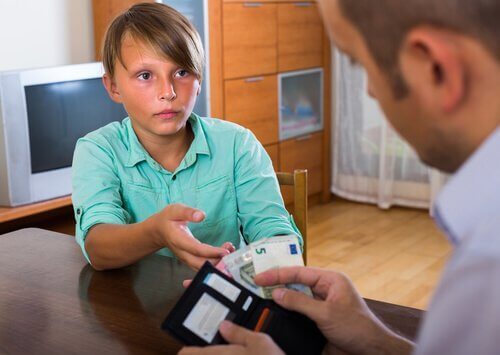 Chłopiec wyciągający do taty rękę po pieniądze - jak nauczyć dziecko wartości pieniądza?