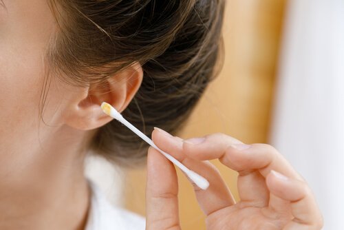 Kobieta czyszcząca ucho patyczkiem - prawidłowa higiena uszu