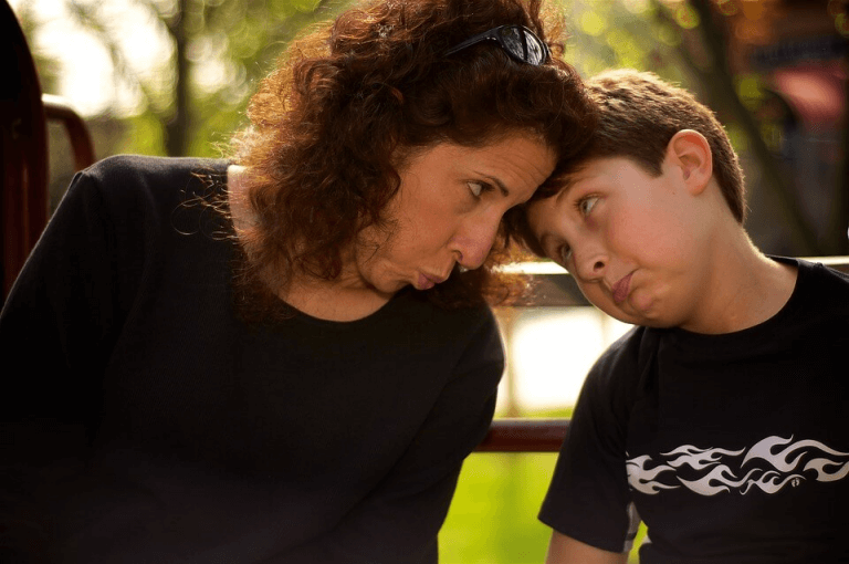 Mama i syn z ustami wygiętymi w podkówkę, dotykający się czołami