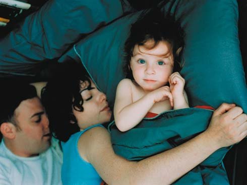 Mama i tata leżący w łóżku z dzieckiem - problemy ze snem