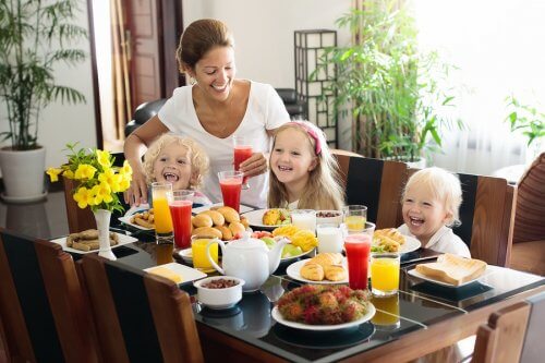 Mama z trójką dzieci przy stole podczas śniadania