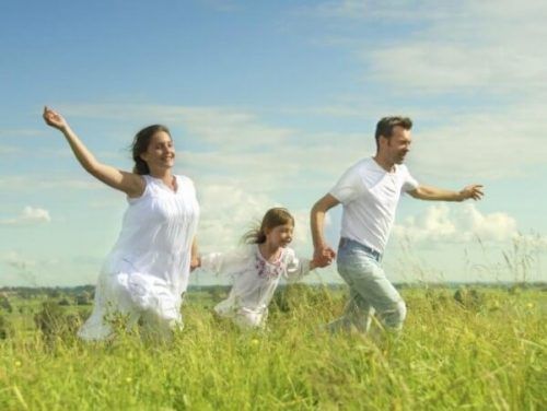 Szczęśliwa rodzina w białych strojach biegnie po łące