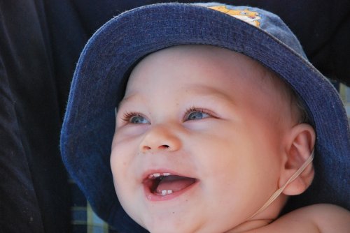 Roześmiane dziecko w kapeluszu z jednym zębem - pierwszy ząb dziecka
