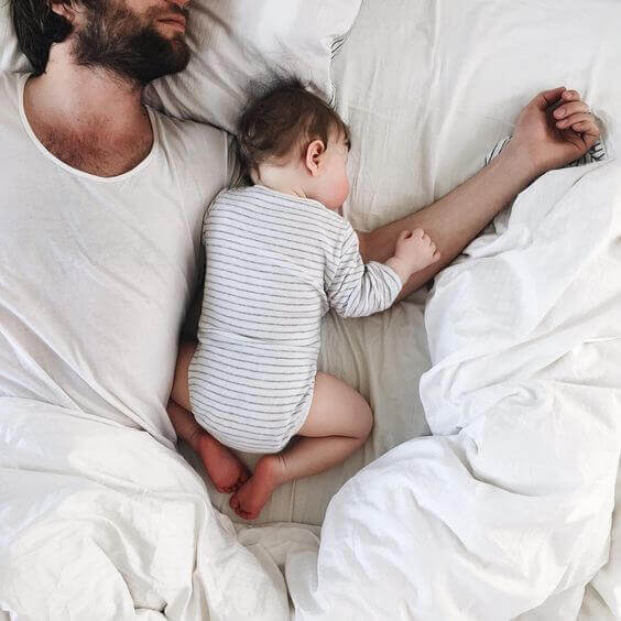 Tata leżący na łóżku z niemowlakiem