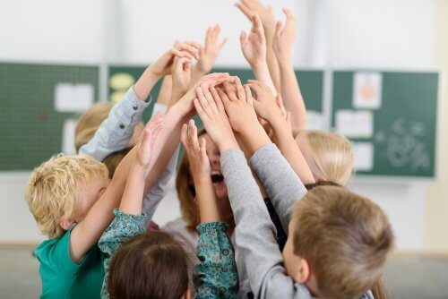 Dzieci w kółku podnoszące ręce do góry - kontekst szkolny