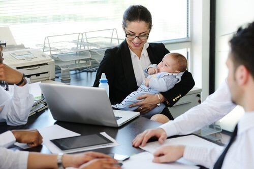 Kobieta na spotkaniu w pracy z dzieckiem - powrót do pracy po urlopie macierzyńskim