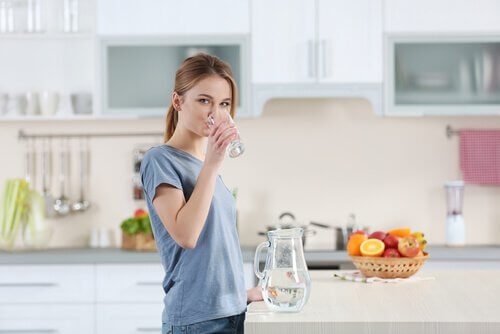 Kobieta pijąca wodę ze szklanki - zadbaj o nawilżenie skóry