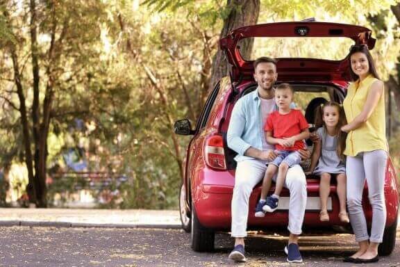 Rodzina siedząca w otwartym bagażniku samochodu - minivany dla dużej rodziny