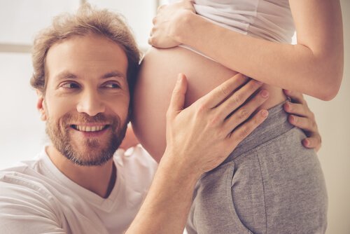 Tata przytulający się z uśmiechem do brzucha w ciąży