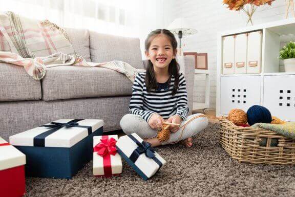 Uśmiechnieta dziewczynka siedząca na podłodze, otoczona prezentami
