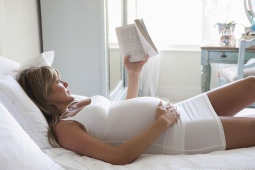Kobieta w ciąży czyta w łóżku