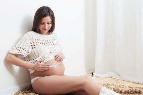 Kobieta w ciąży smarująca swój brzuch