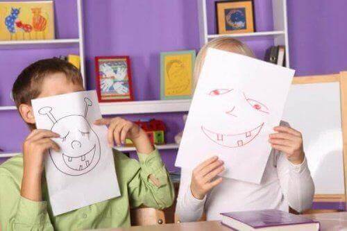 Dzieci zakrywające twarze kartkami z rysunkami