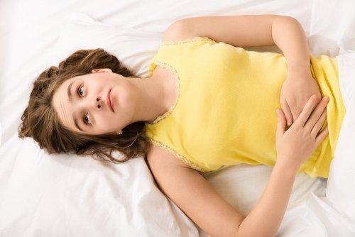 Nastolatka trzymająca się za brzuch - zmiany cyklu miesięcznego w okresie dojrzewania