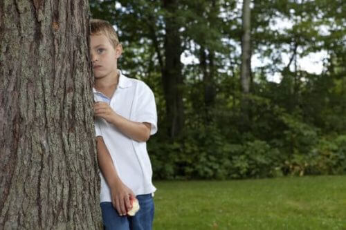Chłopiec chowa się za drzewem
