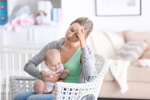 Zmęczona mama trzyma niemowlę - jak zapobiegać depresji poadopcyjnej