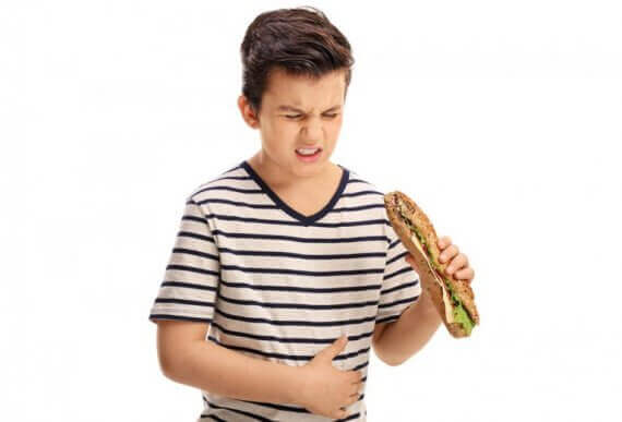 Chłopiec z kanapką w dłoni trzymający się za brzuch