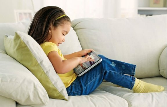 Dziewczynka siedząca na kanapie z tabletem