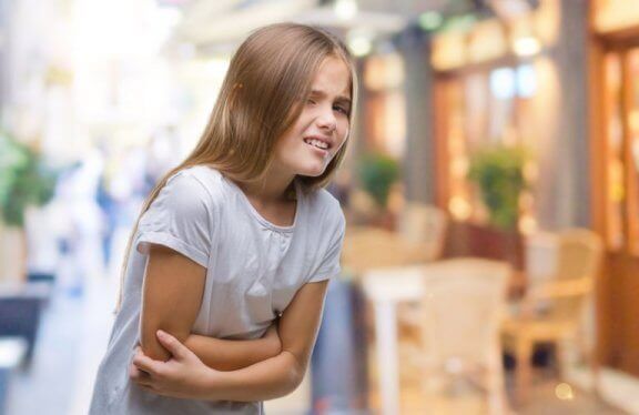 Dziewczynka trzymająca sie za brzuch - niestrawność u dziecka