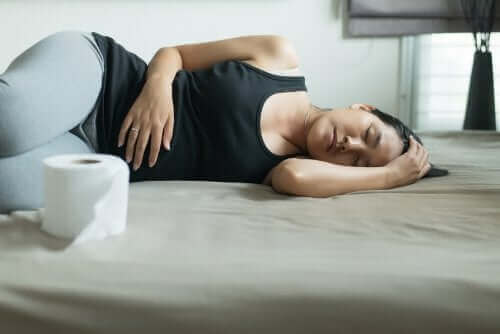 Kobieta leżąca na ziemi, trzymająca się za brzuch