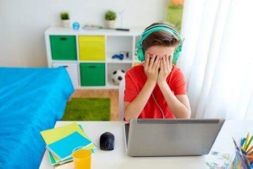 Cyberprzemoc w szkole - chłopiec płacze przed komputerem