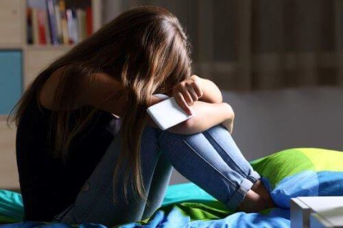 Problemy w szkole - dziewczyna płacze z telefonem w ręku