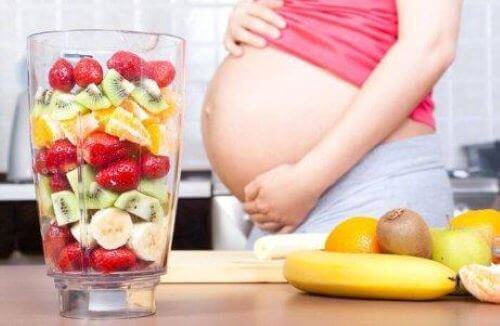 Odżywianie w ciąży - ciężarna kobieta szykuje koktajl owocowy