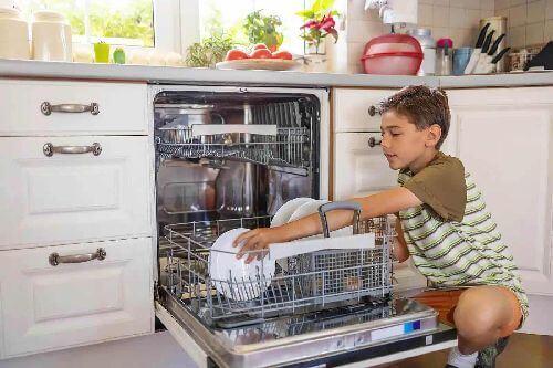 Dziecko wyjmuje naczynia ze zmywarki